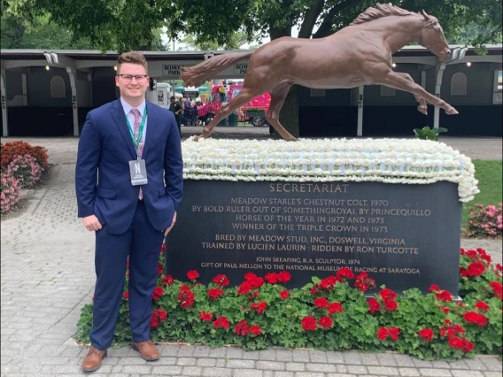 Eric DeCoster standing by a statue