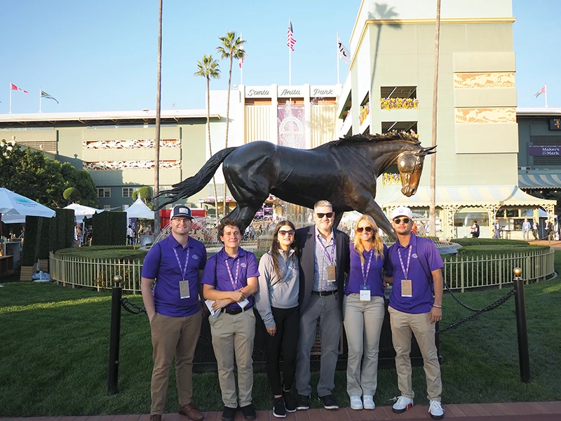 Students standing in front of horse statue