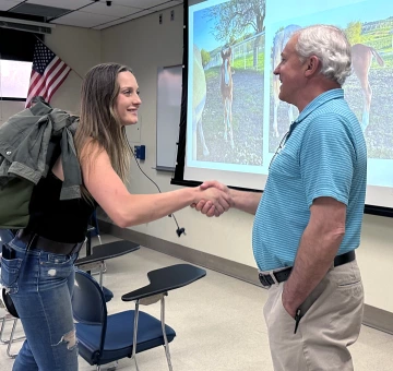 Tom Clark shaking hands with a student